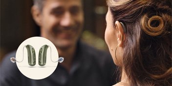  Man och kvinna med Oticon Real hörapparater, i en konversation.