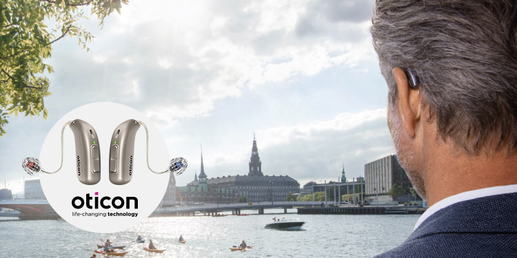 Man med hörapparat från Oticon med stadsvy och vatten i bakgrunden.