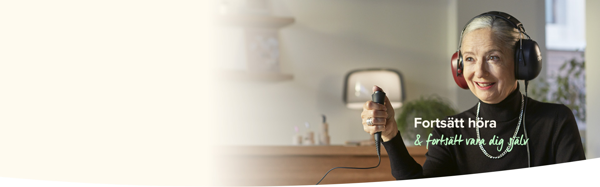  En person bär hörseltesthörlurar och trycker på en knapp i en ljus miljö. Text: 'Fortsätt höra & fortsätt vara dig själv.' Möbler och växter syns i bakgrunden.
