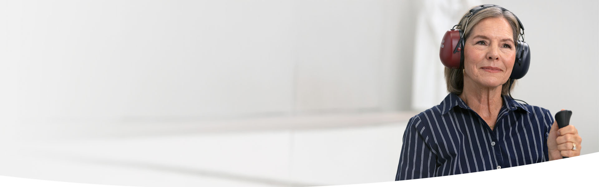 En kvinna som håller i en knapp under ett hörseltest hos Audika