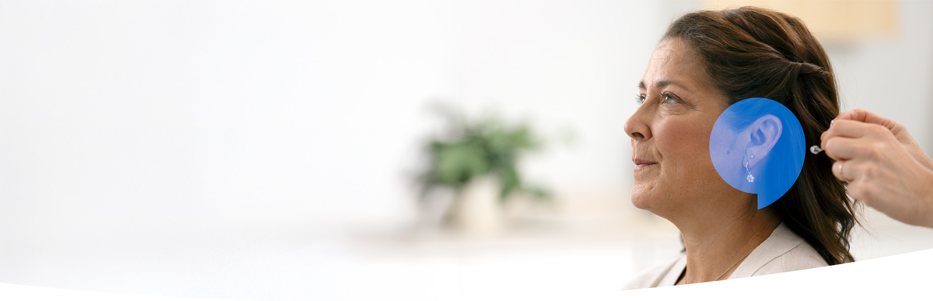 Bild på en kvinna som provar en hörapparat kostnadsfritt hos Audika