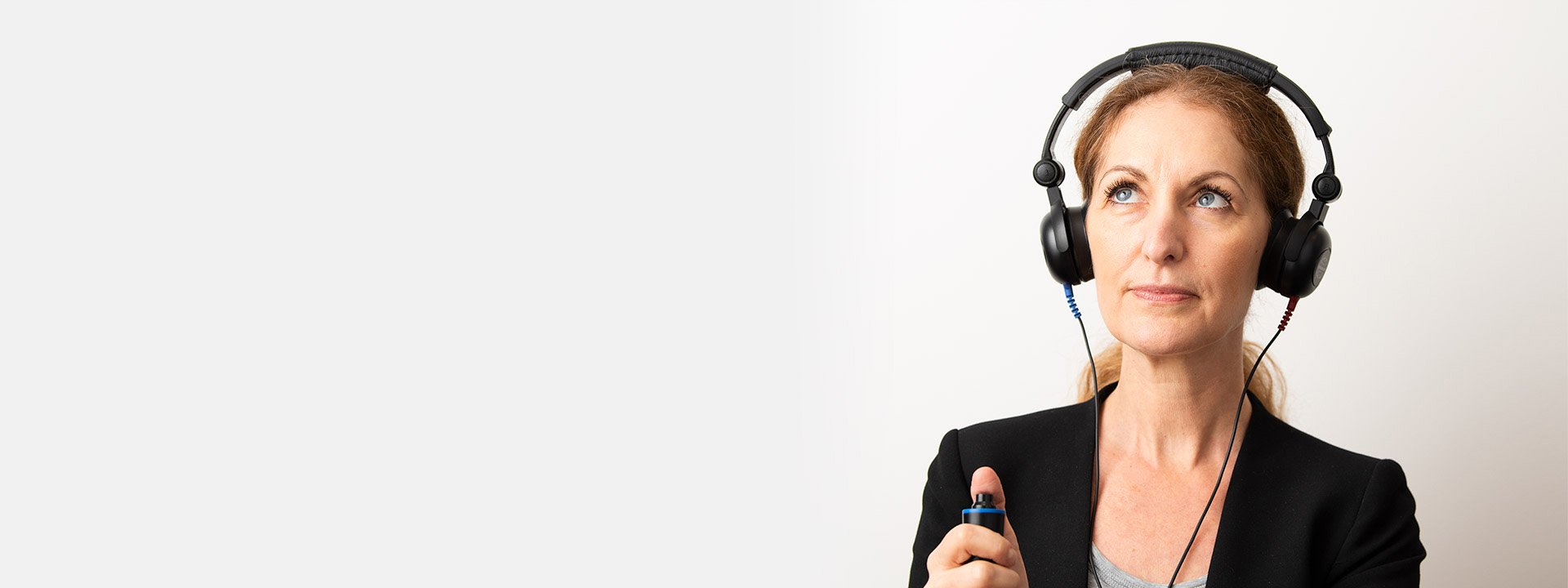  Kvinna gör hörseltest med hörlurar och knapp för att identifiera hörselnedsättning.
