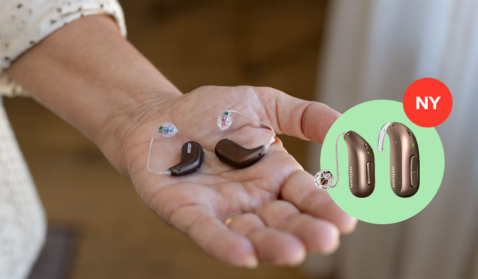 Kvinna som håller Oticon Intent hörapparater i handen.
