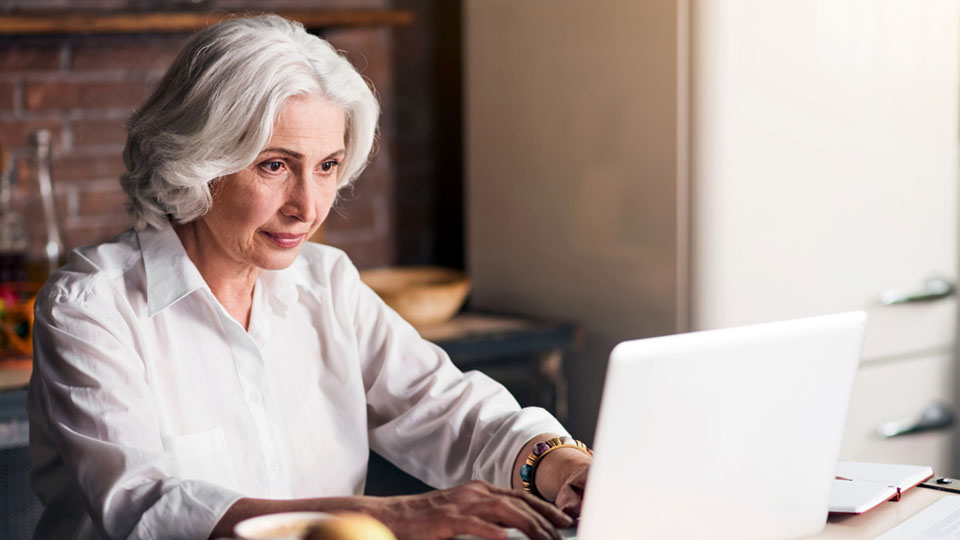 Bild på en kvinna som sitter framför en dator och gör ett online test som ger indikation på tinnitus