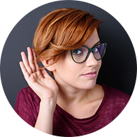 Bild en tjej som har handen bakom handen för att höra vad hon uppfattar som mummel som är ett tecken på nedsatt hörsel.