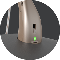 Närbild på hörapparat i som är uppladdningsbar och som sitter i en laddningsstation.