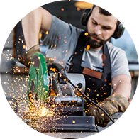  Man arbetar med en slipmaskin som genererar gnistor i en bullrig arbetsmiljö som kan orsaka hörselskador.