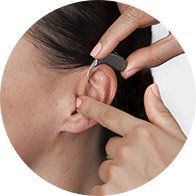  En person som provar ut hörapparaten Oticon Real hos Audika, med möjlighet att ta del av Audikas kunderbjudande.