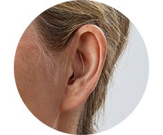 Visar örat på en kvinna som har en Oticon Zeal hörapparat