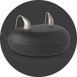  Uppladdningsbara hörapparater i en modern laddningsstation med mörk bakgrund.