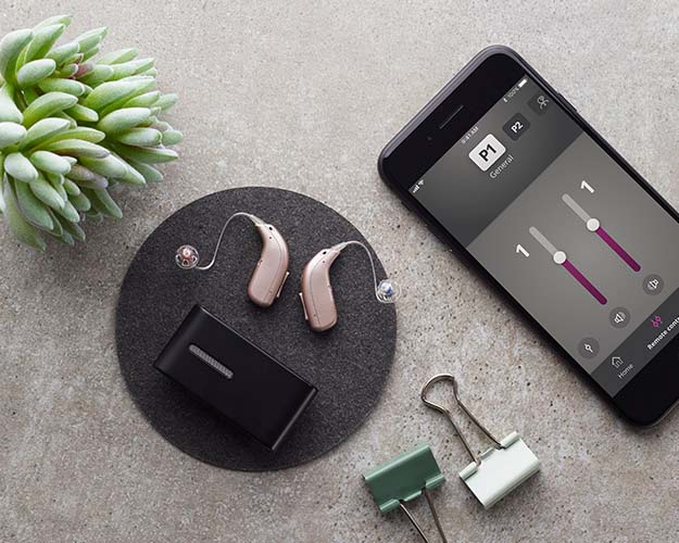 Bild på en en hörapparat med engångbatterier som ligger bredvid tillbehör