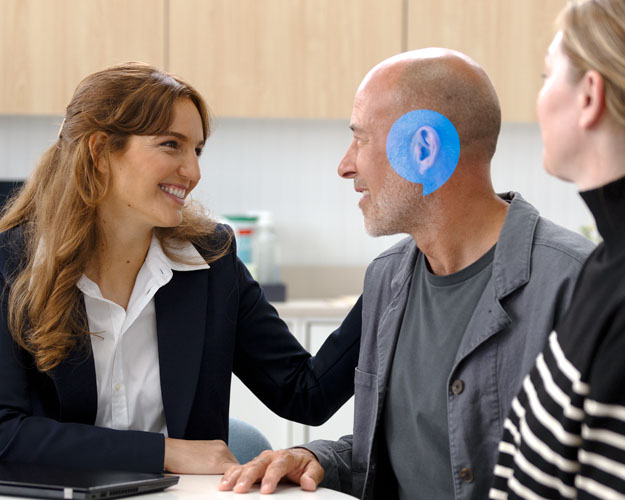 Audionom förklarar för kund om Audikas vision och Audikas mervärdespaket. De är på en klinik.