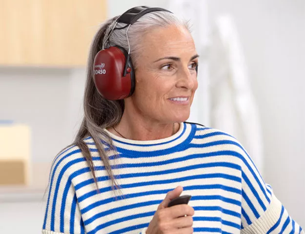  Kvinna med hörlurar som genomför hörseltest på Audikas hörselklinik med hjälp av legitimerade audionomer.