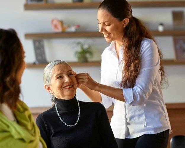  Kvinna får hjälp med att justera hörapparat från regionens eller landstingets sortiment.