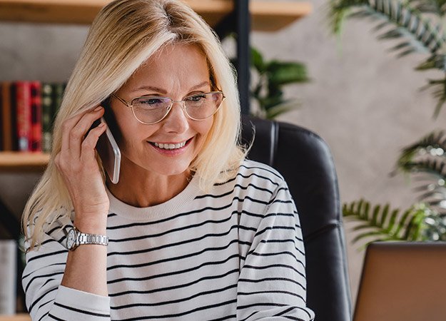  Kvinna i randig tröja pratar i telefon med Audikas kundservice.