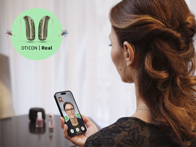  Kvinna med Oticon Real-hörapparat som videosamtalar på mobiltelefon.