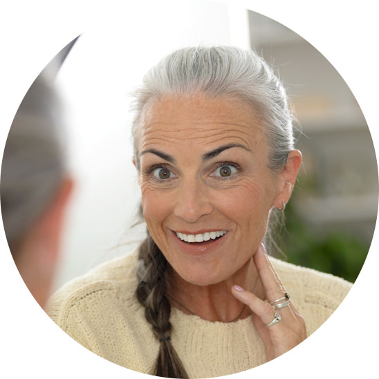 Bild på en kvinna som tittar sig i spegeln och har fått hörselvård i Stockholm