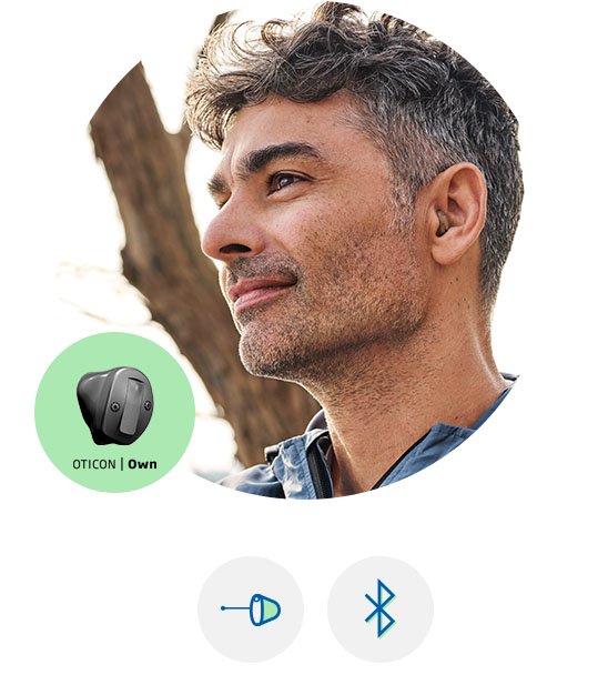 Man som bär en hörapparat som heter Oticon Own och sitter i  örat