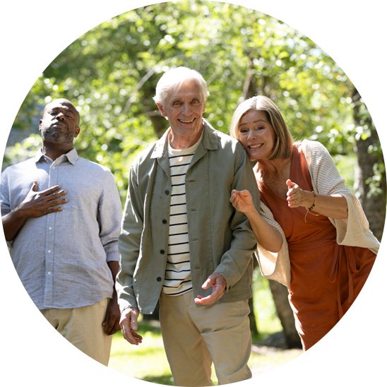  Tre personer med hörselnedsättning promenerar utomhus i en grönskande park.