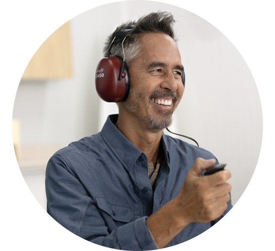  En man utför ett hörseltest med hörlurar och en knapp hos Audika hörselklinik.