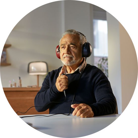  Man utför hörseltest med hörlurar och signalknapp hos Audika i en ljus och modern miljö.