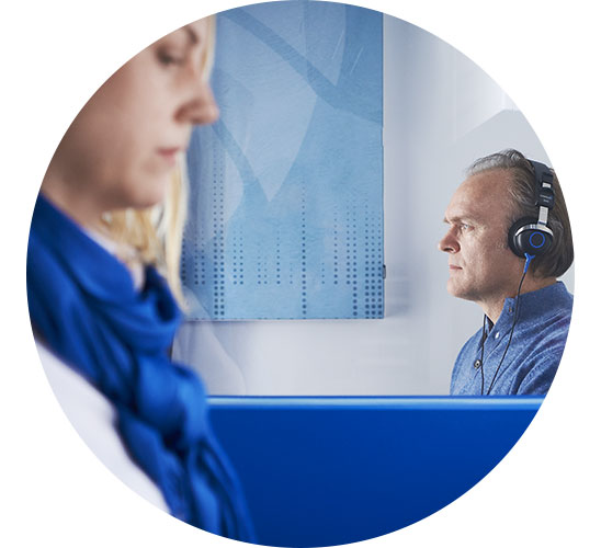  En audionom genomför ett hörseltest på en man i Skåne som bär hörlurar.