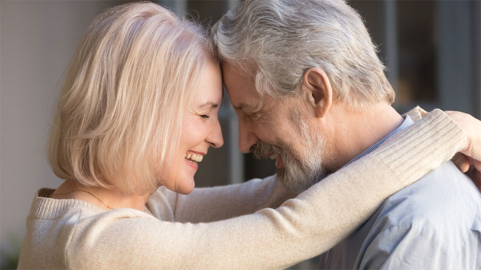 Elderly couple embracing, symbolizing connection and improved communication through hearing care.