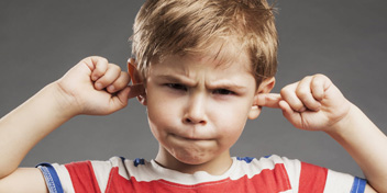 Child plugging ears with fingers, addressing ear-popping sensation.