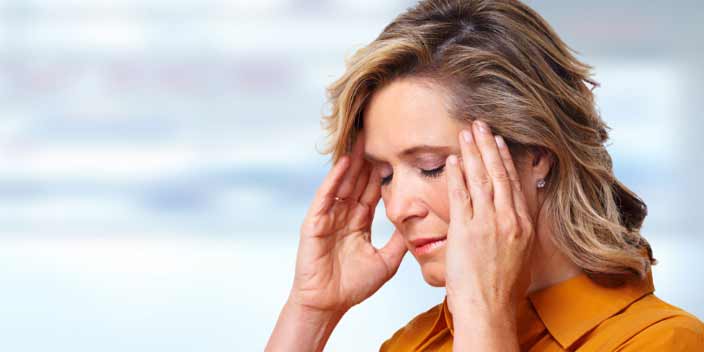 Woman holding her head with both hands, experiencing tinnitus symptoms.