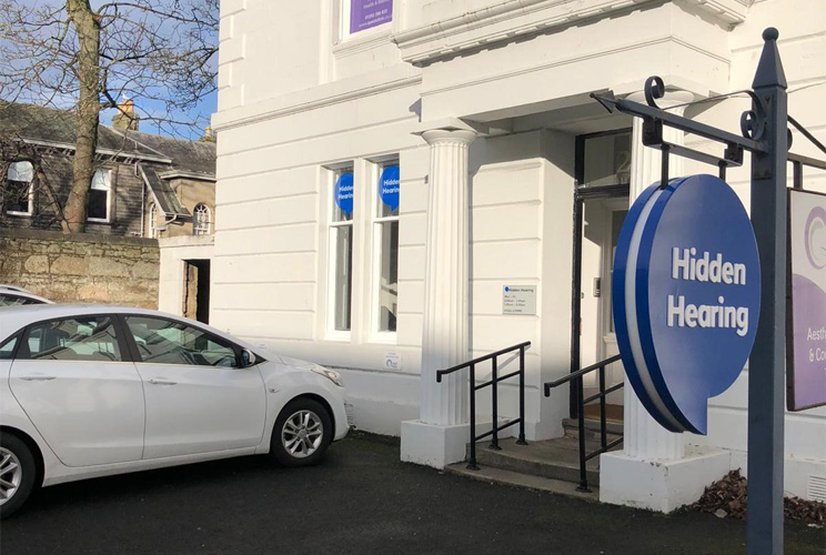 Audika Ayr Hearing Centre exterior with a parked white car and visible signage.