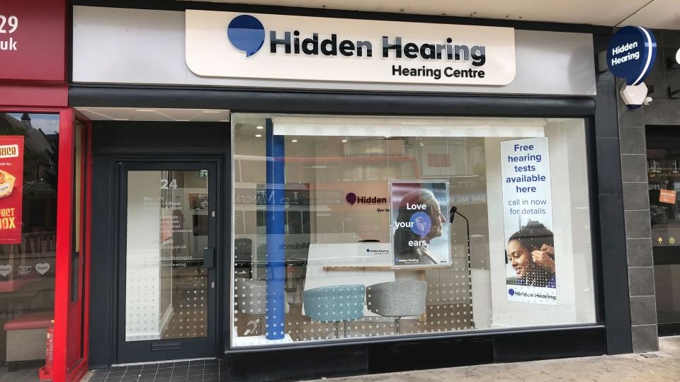 Audika Solihull clinic storefront with signage and promotional materials visible through the window.