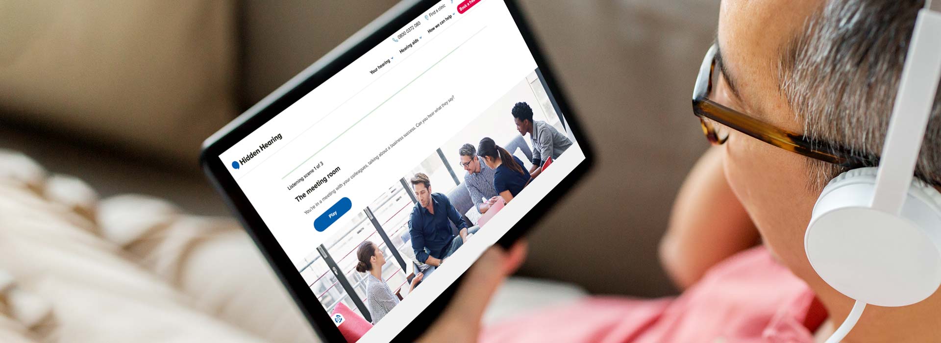 Online hearing test available on Audika’s website, displayed on a tablet held by a person wearing headphones.