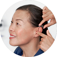 Hearing care specialist fitting a digital hearing aid on a woman’s ear