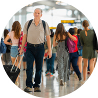 Older man with age-related hearing loss walking through a busy airport, unable to hear announcements.