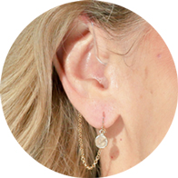 Hearing aid adorned with a DeafMetal Cat’s Eye jewelry attachment featuring a stylish chain and gemstone accent.