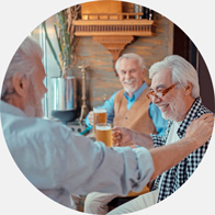 Three older friends enjoying drinks and conversation at a cozy pub.
