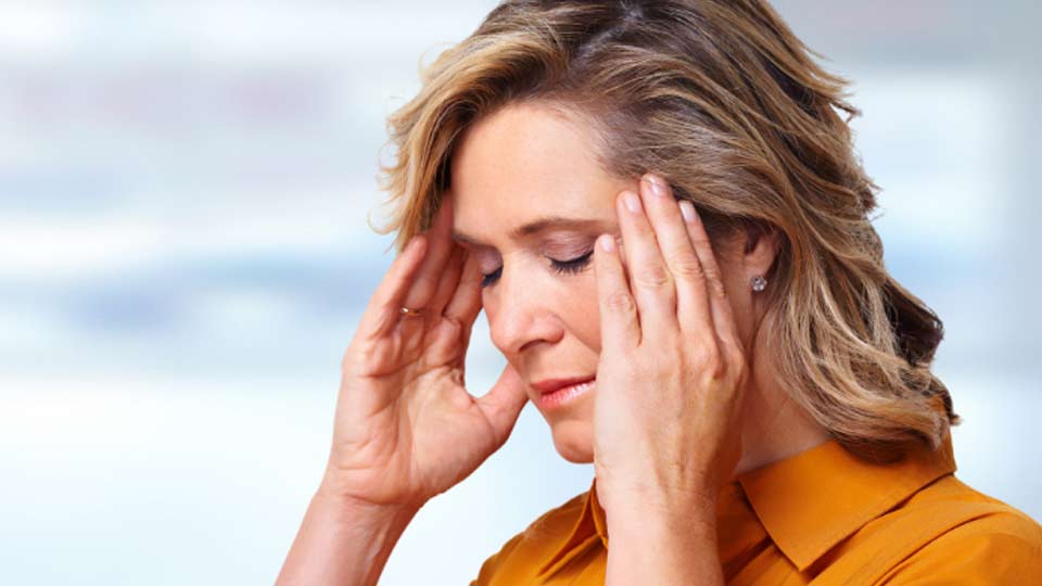 Woman experiencing tinnitus symptoms, holding her hands near her ears.