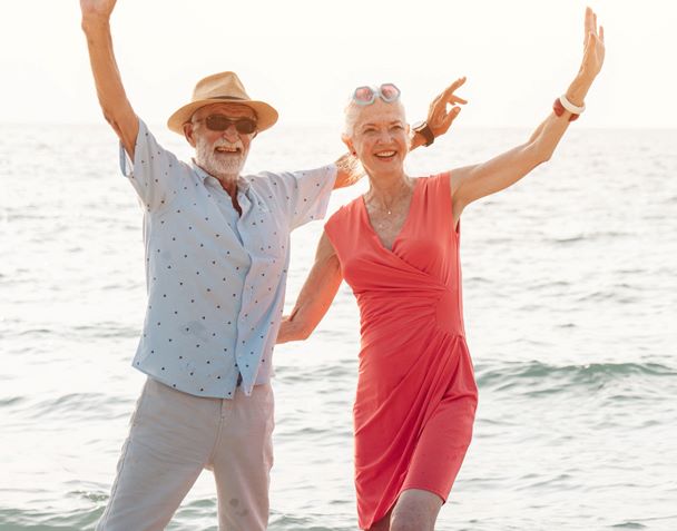 A couple with hearing loss wave at the beach