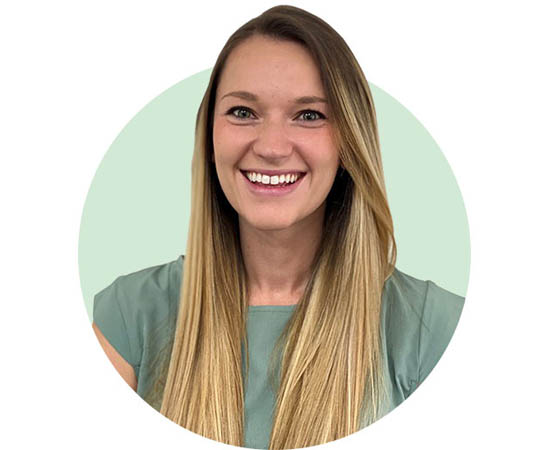 Audika audiologist Grace in a light green blouse, positioned against a soft green background.