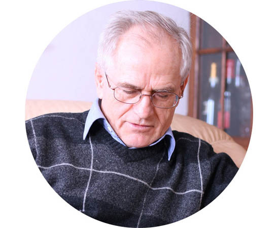 Elderly man resting in a comfortable armchair with a relaxed posture.