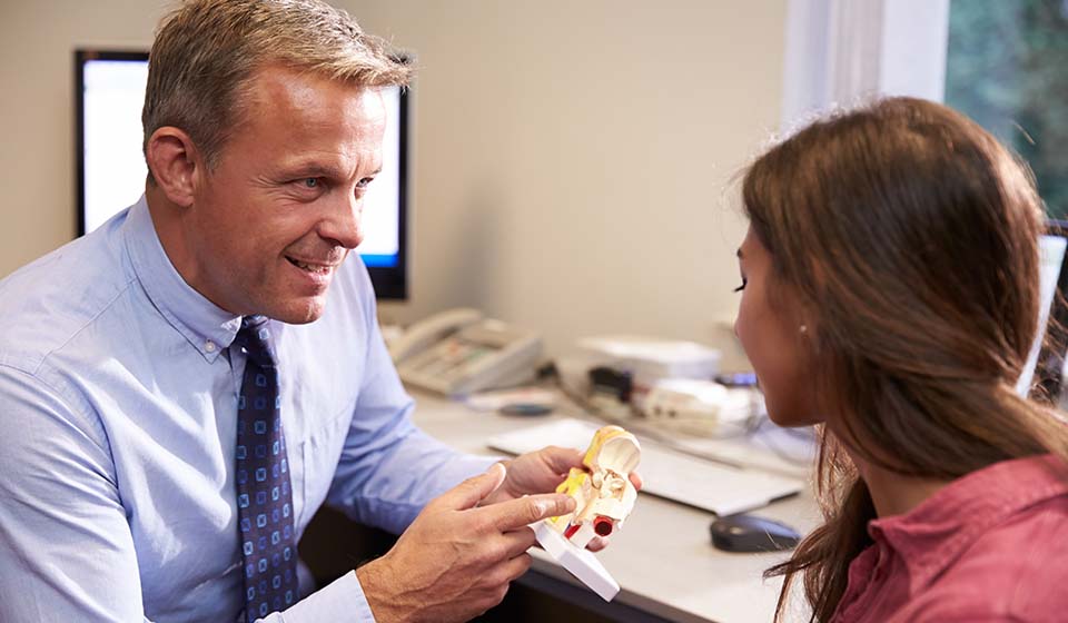 [OPT] Hearing specialist explaining ear anatomy to a patient using a 3D ear model.