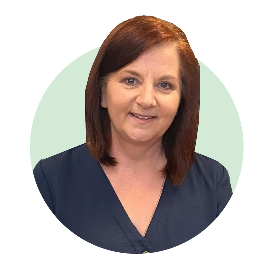 A woman with shoulder-length auburn hair wears a navy blue V-neck top, set against a pastel green circular background. Her face is blurred, leaving her identity unrecognizable. No text is visible.