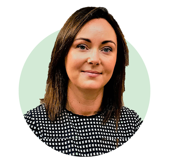 A person with shoulder-length brown hair wearing a black-and-white patterned top, set against a solid light green circular background. The face is intentionally blurred for privacy. No text is present.