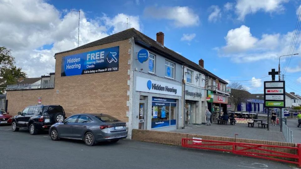 A photograph of the exterior of the Hidden Hearing Artane clinic location with signage on the wall outside pointing out the offer or Free Hearing Health Checks