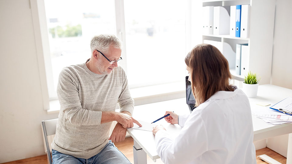 Man pointing at form with audiologist