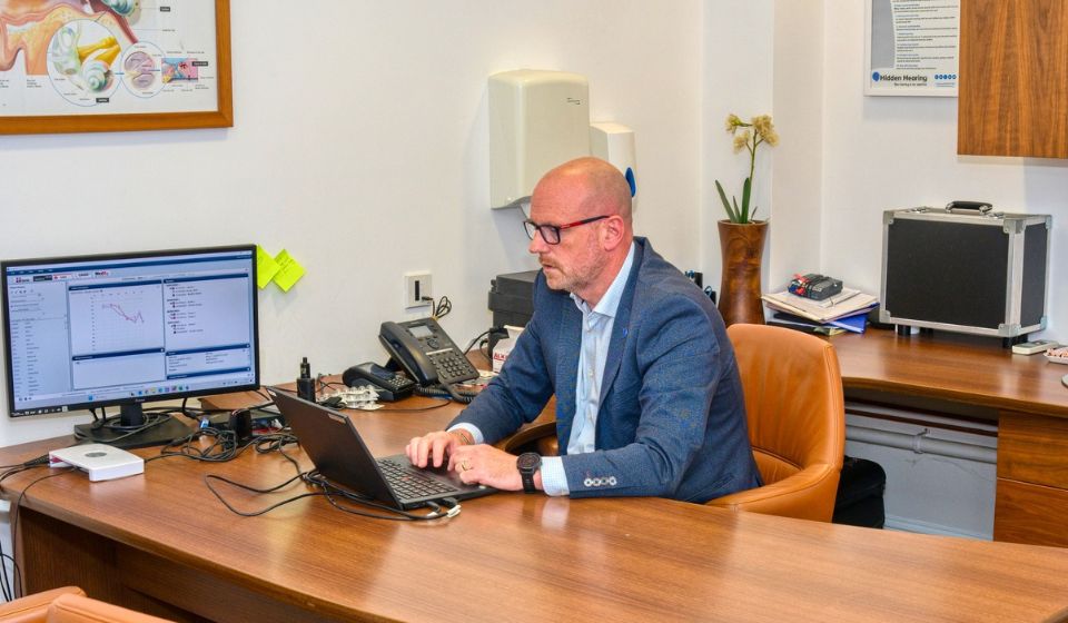 Hidden Hearing audiologist Tim Owens working at his desk