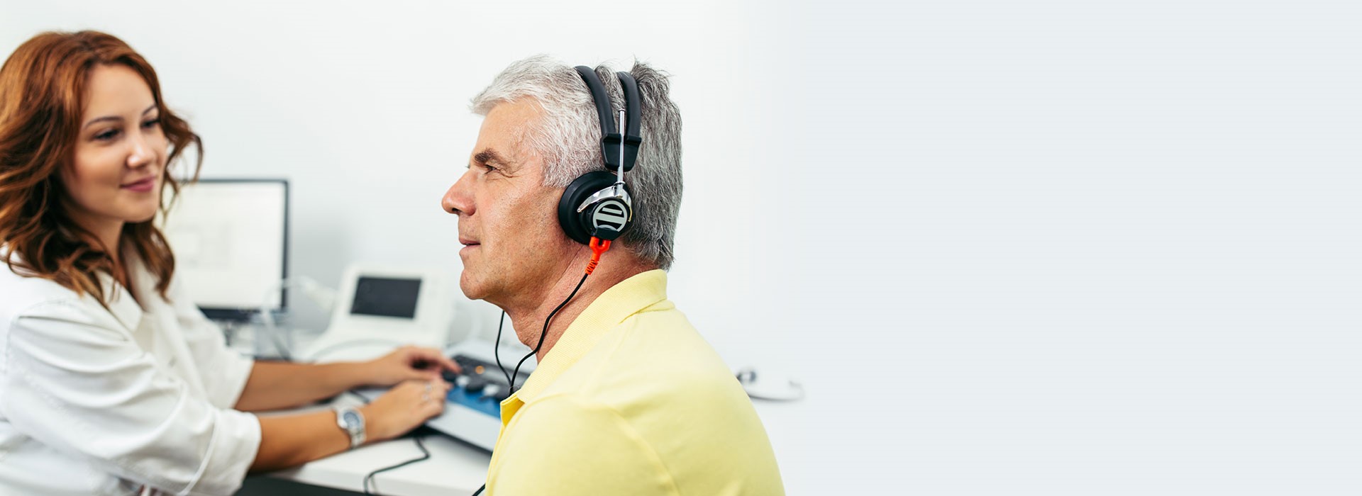 man undergoing hearing test with audiologist conducting assessment