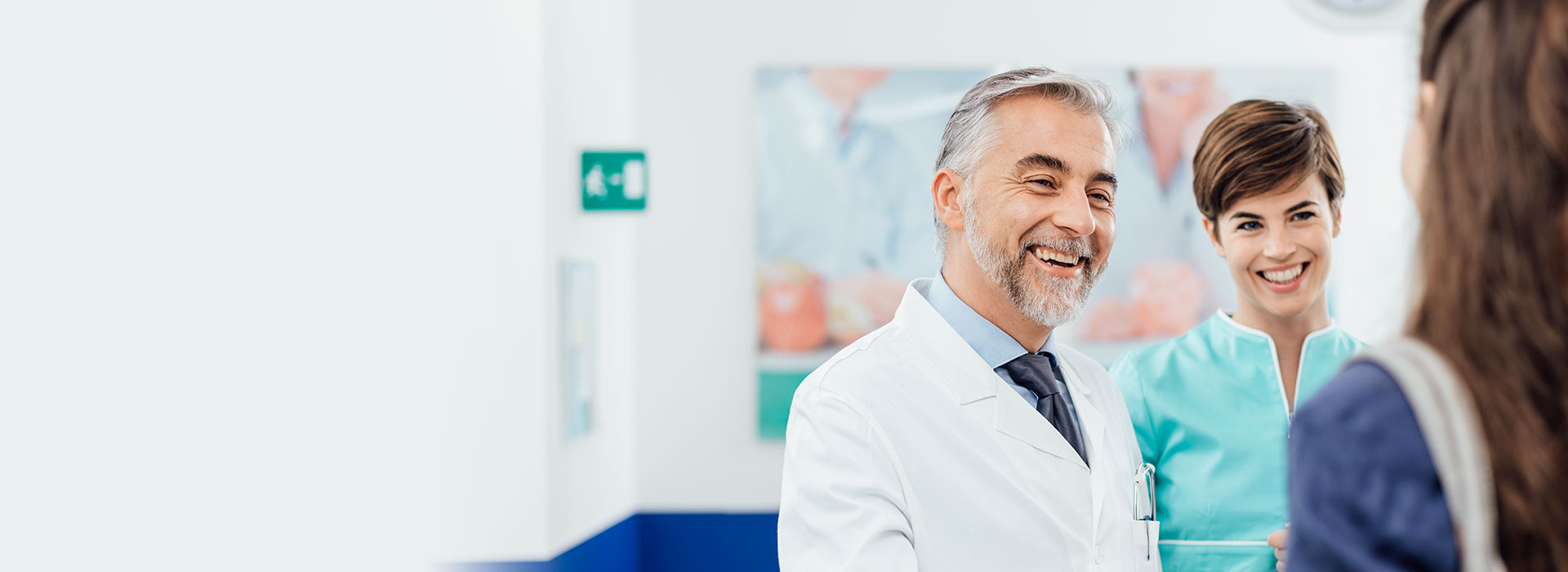 Hearing care specialist and assistant speaking with a patient in a clinic setting.