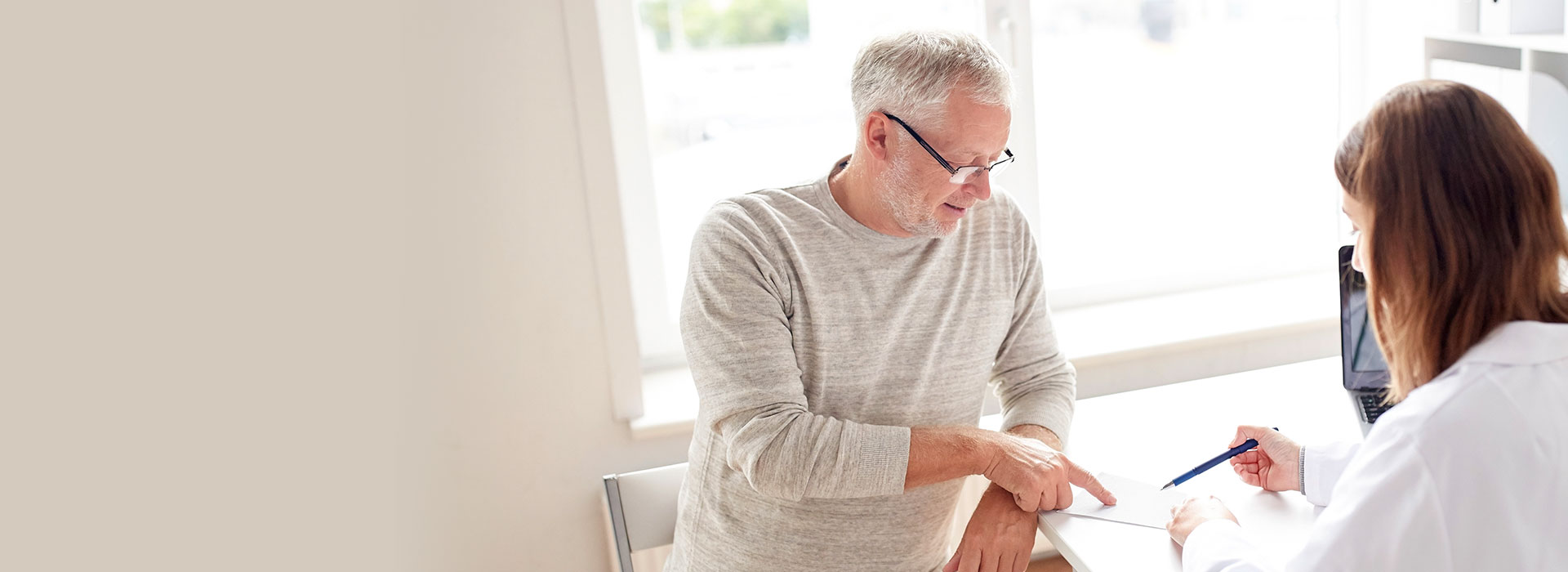 Senior man consulting with a hearing care professional in a bright office.