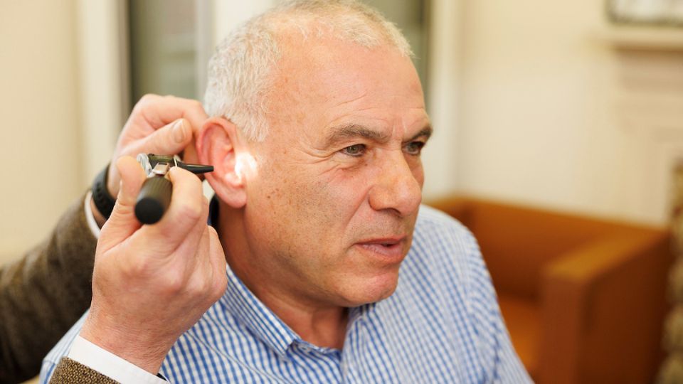 audiologist performing an ear examination on an older man